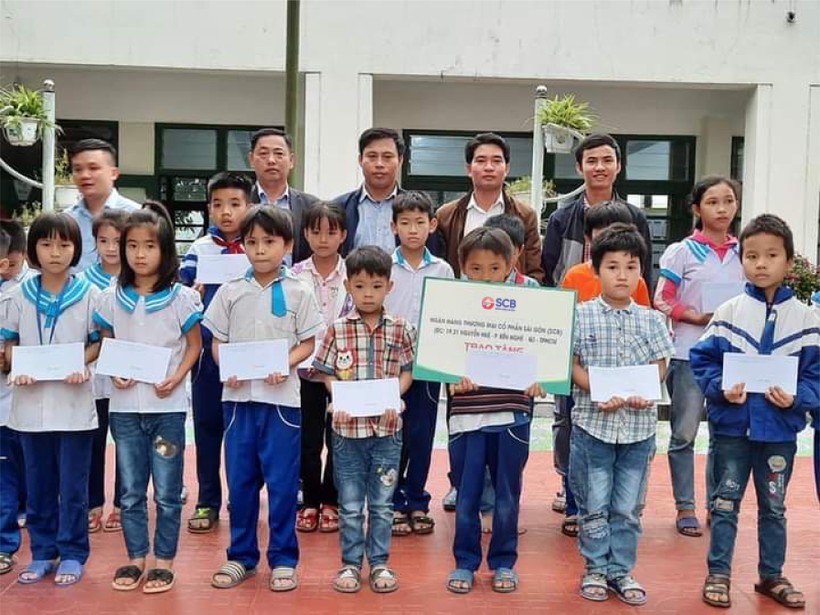 Đại diện SCB trao quà và phần tiền ủng hộ cho các em học sinh mầm non và tiểu học Hồng Lộc, Thụ Lộc, huyện Lộc Hà, tỉnh Hà Tĩnh.