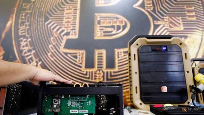 Thiết bị khai thác bitcoin trước logo đồng mã hóa, ảnh chụp ở Đài Loan hồi tháng 6. ẢNH: REUTERS
