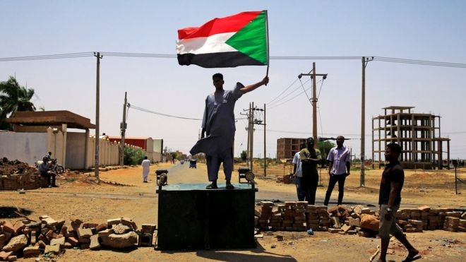 Một người biểu tình Sudan đứng trên hàng rào chắn ở Khartoum hôm thứ Tư (ảnh Reuters)