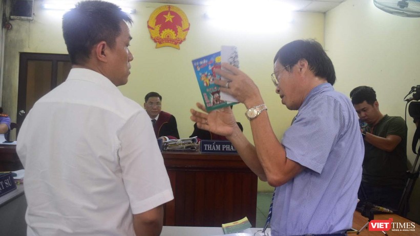 Họa sĩ Lê Linh (áo trắng) và ông Nguyễn Vân Nam (người đang cầm cuốn sách) - đại diện cho công ty Phan Thị với những trao đổi gay gắt tại tòa 