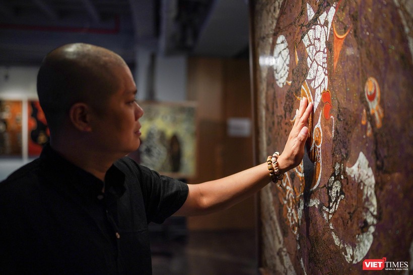 Họa sĩ Trần Ngọc Hưng bên những tác phẩm đang trưng bày tại Ngõ Art Gallery. Ảnh: Phạm Nguyễn 