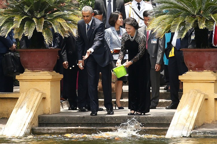 Tổng thống Mỹ và Chủ tịch Quốc hội Nguyễn Thị Kim Ngân cho cá trong ao cá Bác Hồ ăn. (Ảnh: Reuters)