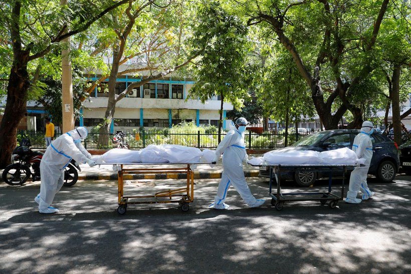 Nhân viên y tế mặc thiết bị bảo vệ cá nhân (PPE) khiêng thi thể của những người nhiễm COVID-19 (Ảnh: Reuters)