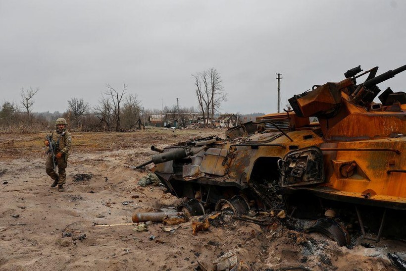 Một binh sĩ Ukraine kiểm tra xác xe thiết giáp của quân đội Nga gần Kiev (Ảnh: Reuters)