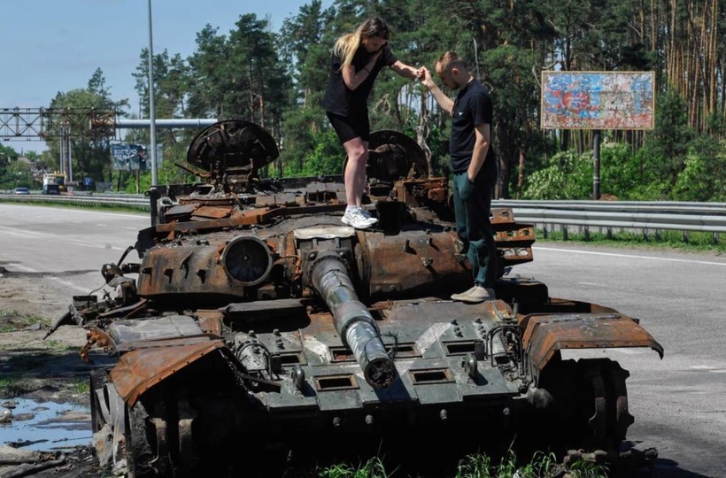 Một cặp đôi tò mò đứng trên chiếc xe tăng Nga bị phá hủy ở Kiev, Ukraine (Ảnh: DPA)