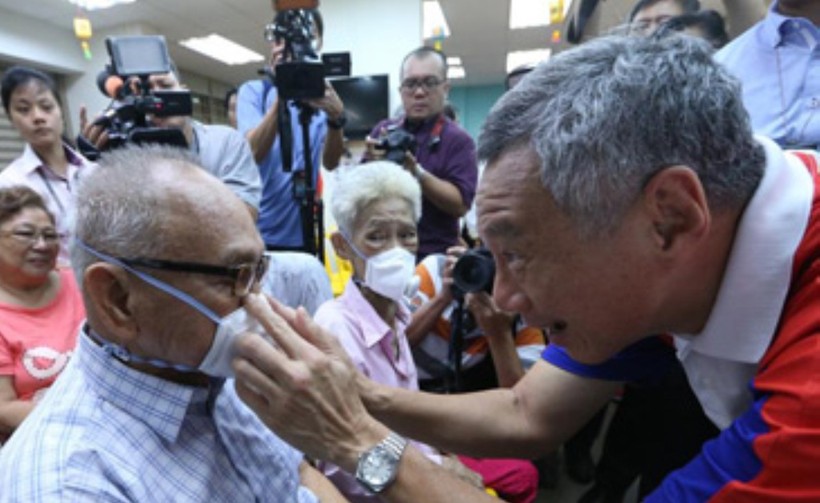 Do dịch bệnh bùng phát trở lại, Singapore ban hành lệnh bắt buộc người ra đường phải đeo khẩu trang. Trong ảnh: Thủ tướng Lý Hiển Long đeo khẩu trang cho người dân (Ảnh: Guancha).