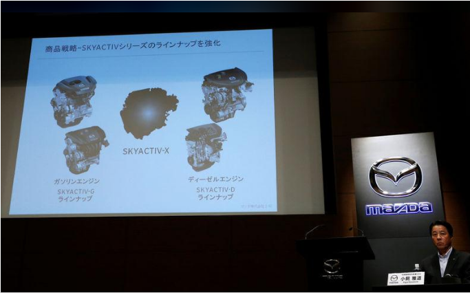 Chủ tịch hãng Mazda Masamichi Kogai bên cạnh màn hình giới thiệu động cơ mới tại cuộc họp báo ở Tokyo ngày 8/8. Ảnh Reuters