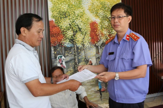 Đại diện VKSND huyện Bình Chánh, TP.HCM trao quyết định đình chỉ vụ án, đình chỉ bị can cho ông Tấn - Ảnh: Gia Minh