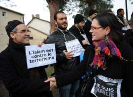 Một phụ nữ với biểu ngữ "Je suis Charlie" bắt tay một người Hồi giáo đang mang biểu ngũ "Hồi giáo  chống chủ nghĩa khủng bố" trong khu phố Sablons của Le Mans, miền tây nước Pháp, ngày 10.01.2015. Ảnh AFP