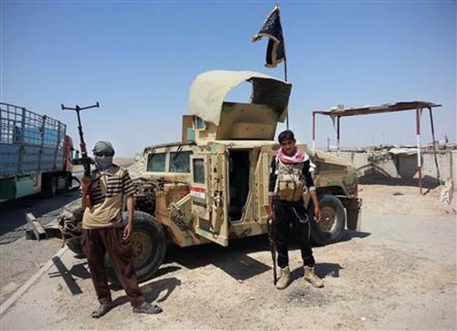 Phiến quân IS đứng cạnh một xe Humvee chiếm được của Iraq tháng 6/2014. Ảnh: AP