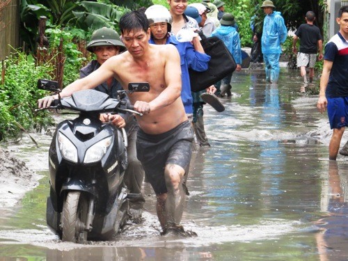 Người dân phải lội bùn, di dời một số vật dụng ra khỏi khu vực ngập. Ảnh: Giang Chinh.
