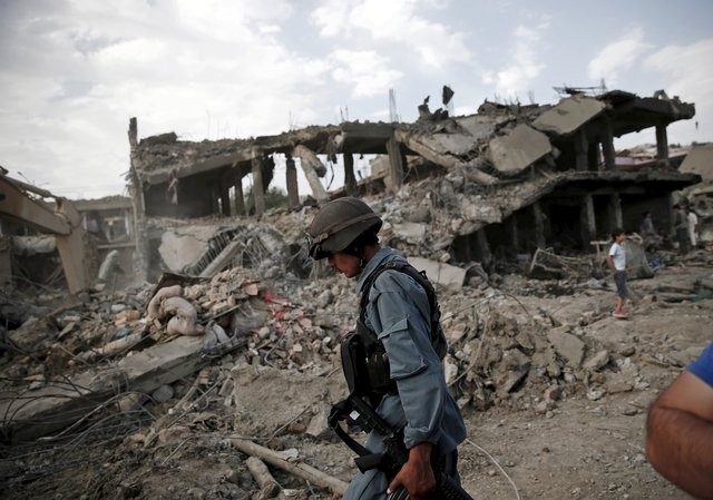 Một cảnh sát Afghanistan tại hiện trường vụ đánh bom xe - Ảnh: Reuters
