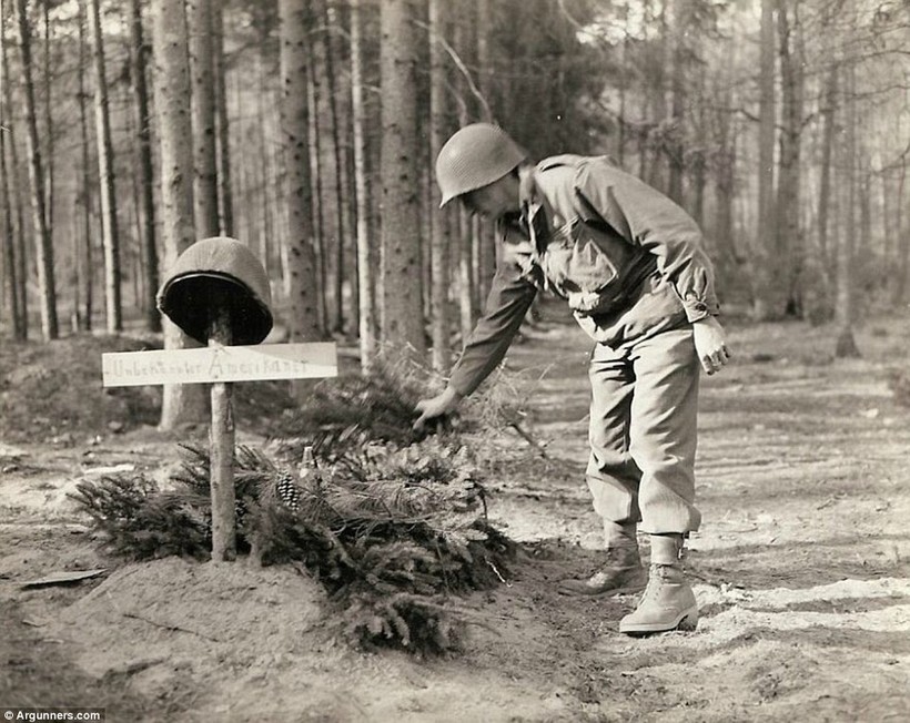 Một lính Mỹ đặt các cành thông lên mộ của lính Mỹ vô danh, bị quân Đức chôn trước khi rút lui.