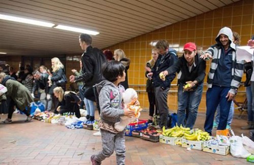 Em bé tị nạn được người tình nguyện nhiệt tình tiếp đón tại nhà ga Hamburg, Đức