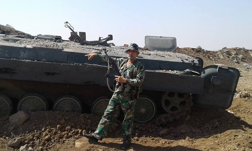 Một binh sĩ lực lượng đặc nhiệm Nga trên chiến trường Hama, bên một xe BMP của phiến quân bị hủy diệt - ảnh Masdar News
