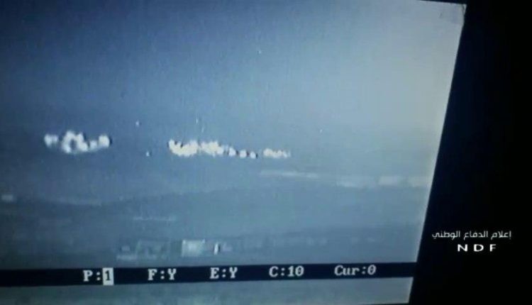 Cảnh pháo phản lực Grad tấn công nhóm chiến binh HTS trên vùng nông thôn Bắc Hama trên màn hinh UAV - ảnh Muraselon