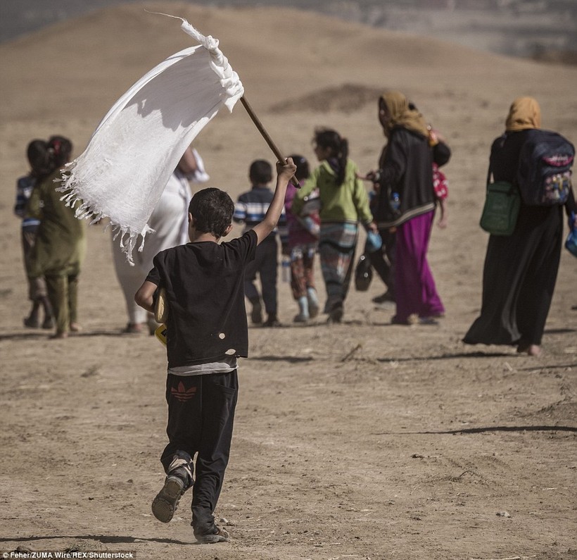 Một em nhỏ cầm cờ trắng trong dòng người chạy thoát khỏi Mosul
