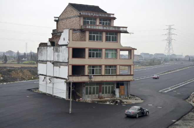 Một ngôi làng ở Chiết Giang bắt đầu di dời để phục vụ việc làm đường cao tốc. Tuy nhiên, đôi vợ chồng già kiên quyết không chuyển nhà. Giới bất động sản đặt tên cho những ngôi nhà kiểu này là “nhà đinh”. Ảnh: China Daily Infor.