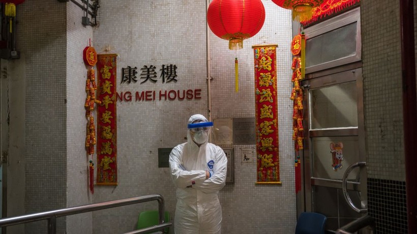 Một nhân viên y tế mặc đồ bảo hộ đứng bảo vệ bên ngoài lối vào tòa nhà chung cư ở Tsing Yi (Hồng Kông) sau khi phát hiện cư dân thứ hai nhiễm virus tại đây. Hơn 100 người sống tại tòa chung cư này đã được sơ tán (ảnh Getty Images)
