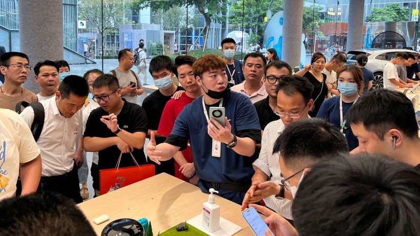 Một nhân viên giới thiệu điện thoại thông minh Huawei Mate 60 tới khách hàng tại cửa hàng của Huawei ở Thâm Quyến (ảnh: Reuters)