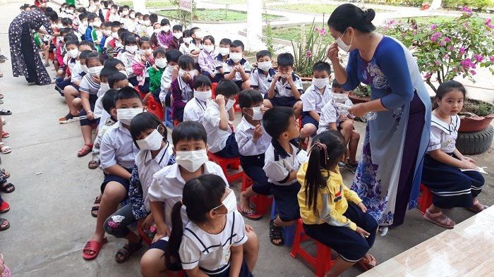 Cô giáo hướng dẫn học sinh trường tiểu học An Bình (Thị xã Hồng Ngự, Đồng Tháp) cách đeo khẩu trang (Ảnh: Sở GD-ĐT Đồng Tháp) 