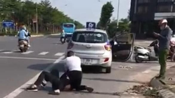 Hình ảnh từ video clip cho thấy Đại uý Công an gọi điện thoại trong khi người lái taxi vật lộn với tên cướp - Ảnh cắt từ clip