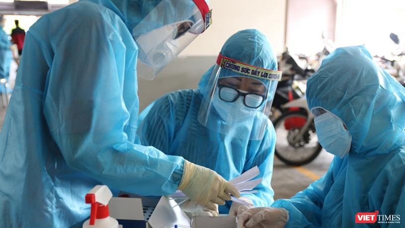 Nhân viên y tế lấy mẫu xét nghiệm trong khu vực phong tỏa - Ảnh: HCDC