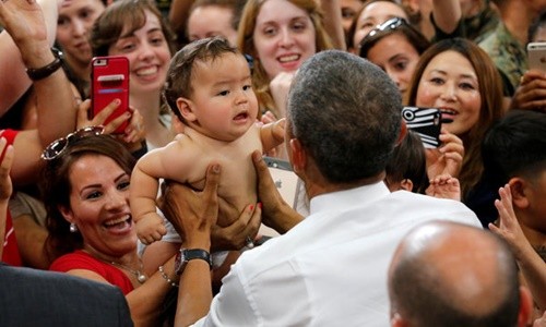 Em bé lập tức nín khóc sau khi được ông Obama bế. Ảnh: Reuters