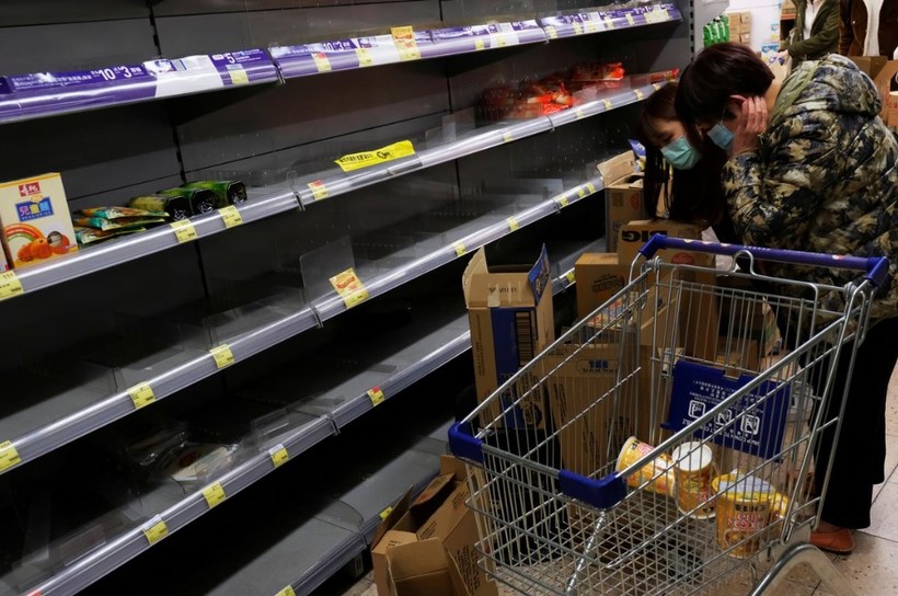 Người tiêu dùng mang khẩu trang đi lung sục các kệ hàng bán mỳ gói để tích trữ (Ảnh: Reuters)