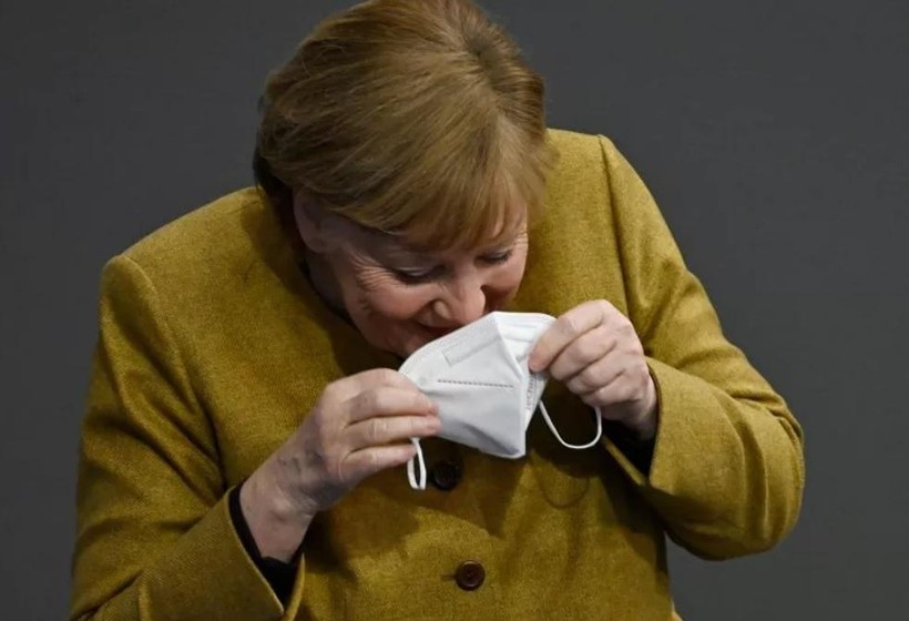 Bà Merkel nhịn cười khi đang đeo lại khẩu trang của mình (Ảnh: Getty)