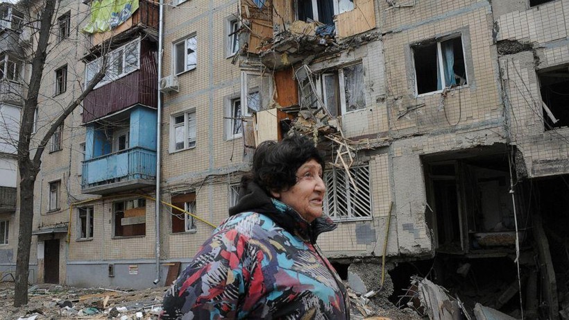 Một người phụ nữ đi qua tòa nhà bị hư hại do pháo kích ở Kharkiv, Ukraine (Ảnh: AP)