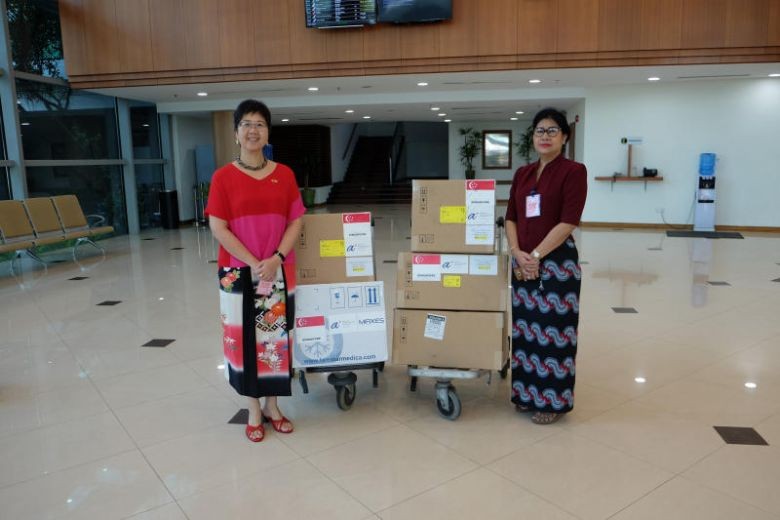 Đại sứ Singapore tại Myanmar - Vanessa Chan (trái) bàn giao các vật tư y tế tài trợ của Singapore cho Giám đốc Phòng thí nghiệm Y tế Quốc gia Myanmar - Htay Htay Tin, bao gồm 3.000 bộ xét nghiệm chẩn đoán và hai máy phản ứng chuỗi Polymerase (PCR) để xét 