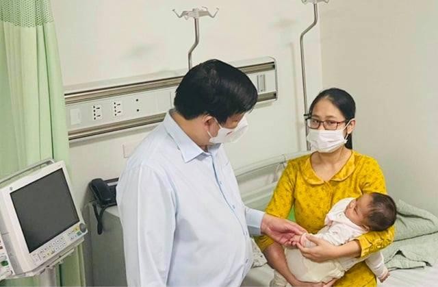 Bộ trưởng Bộ Y tế Nguyễn Thanh Long thăm em bé sau khi tiêm vaccine COVID-19 nhầm tại Trạm Y tế xã Yên Sơn, huyện Quốc Oai (Ảnh - Mạnh Cường) 