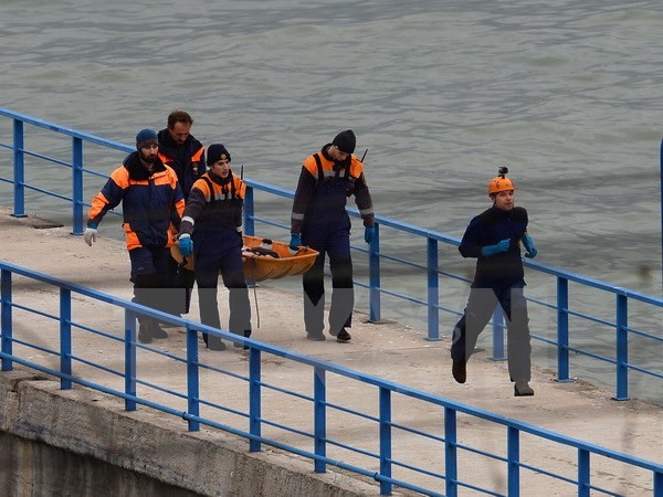 Các nhân viên cứu hộ đưa thi thể nạn nhân vào bờ. (Nguồn: THX/TTXVN)