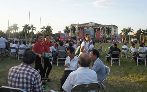 Người dân đến với lễ hội bia, nhận bia lon rồi ngồi xuống bãi cỏ sân vận động, uống. 