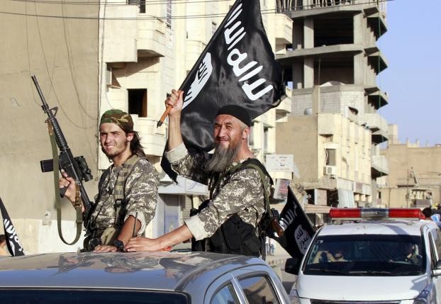 Các tay súng của IS giương cờ khi đi lại trên đường phố Raqqa, Syria. Ảnh: Reuters