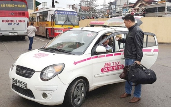 Giá cước taxi ở Hà Nội hiện thấp nhất cả nước (Một khách hàng thanh toán tiền taxi tại Bến xe Lương Yên, Hà Nội) - Ảnh: Dương Linh