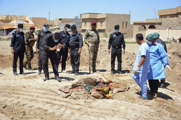 Lực lượng an ninh Iraq cùng nhóm điều tra pháp y xem xét một ngôi mộ tập thể chứa hàng chục thi thể đàn ông, phụ nữ và trẻ em tại sân vận động ở Ramadi, cách Baghdad 115km về phía tây - Ảnh: AP