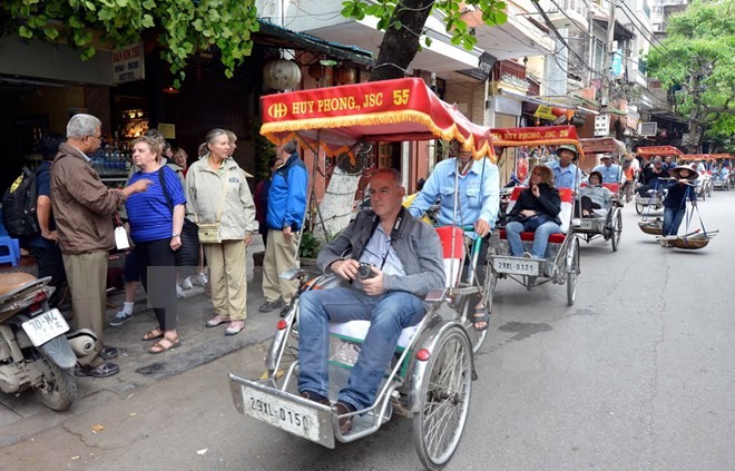 Du khách nước ngoài thăm phố cổ Hà Nội bằng xe xích lô. (Ảnh: Thanh Hà/TTXVN)